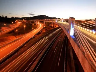 Vista nocturna de una torre de control y autopistas con monitoreo 24/7.