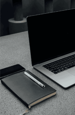 Laptop y cuaderno en oficina, soluciones de rastreo satelital y monitoreo 24/7.