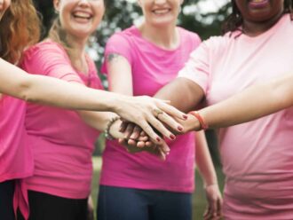 Equipo de mujeres con manos unidas, soluciones en seguridad y monitoreo 24/7.